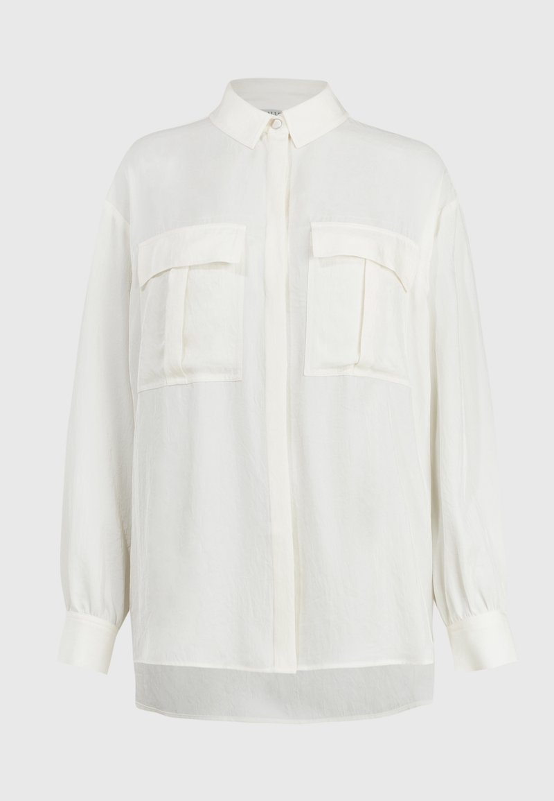 Long-sleeve white shirt with a collared neck, button closure, and two chest pockets; lightweight fabric with a soft, textured finish.