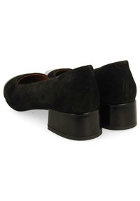 Tacones de ante negro con punta redonda y tacón cuadrado bajo. Textura lisa, con un diseño simple y elegante.