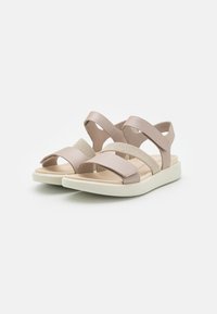 Beige sandaler med blandede materialer, der har krydsremme, elastiske detaljer, en polstret indersål og en hvid sål for komfort.
