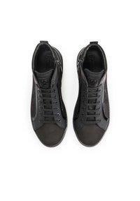 Mustad mustad sneakers, mille nahast ülemise osaga, tekstuuriga külgpaneelide ja silmapaistva nööbistamisega. Lisatud on tõmblukk ja logo keeles.