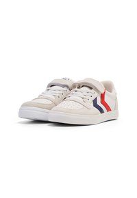 Sneakers z beżową zamszową cholewką, białymi sznurowadłami i rzepem. Posiadają czerwone i niebieskie paski po bokach oraz białą gumową podeszwę.