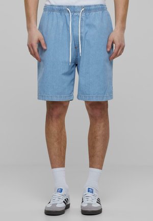 Lyseblå denimshorts med elastisk liv og snor. Har rett ben-design og sydd kant. Komplementert av grå joggesko.