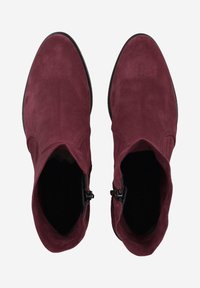 Bottines en suede bordeaux avec une texture lisse, bout pointu et fermeture éclair sur le côté. Profil slim et semelle noire flexible.