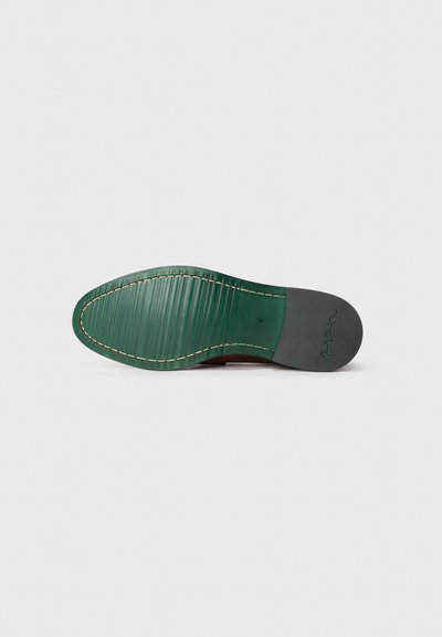 Suela de zapato de cuero con un acabado verde, que presenta estrías horizontales y un contraste de costura crema. Área negra lisa cerca del talón.