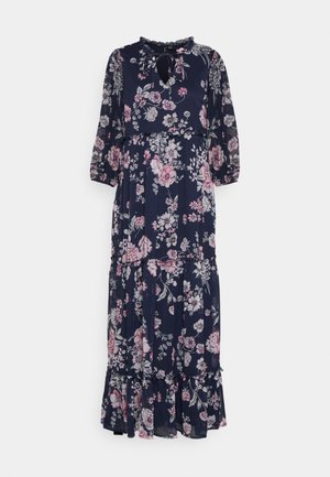Robe longue fleurie bleu marine avec des fleurs roses et blanches. Elle présente un col à volants, des manches trois-quarts et une jupe à volants.