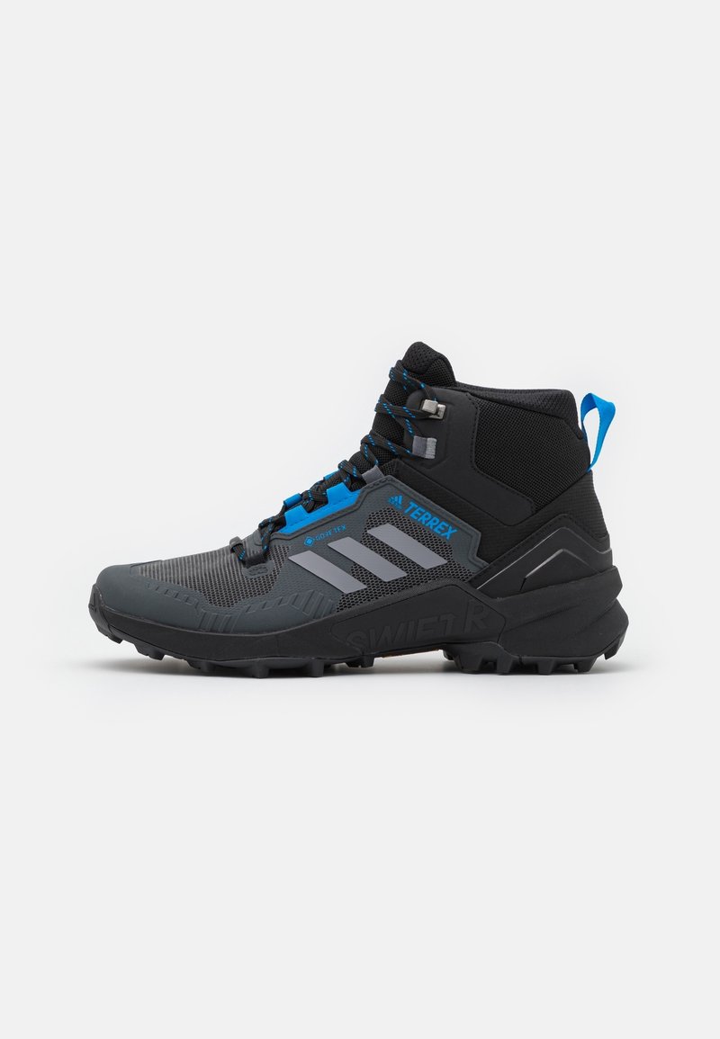 Chaussure de randonnée montante Adidas Terrex noire et grise avec des accents bleus, semelle robuste et tissu en mesh pour une utilisation en extérieur.