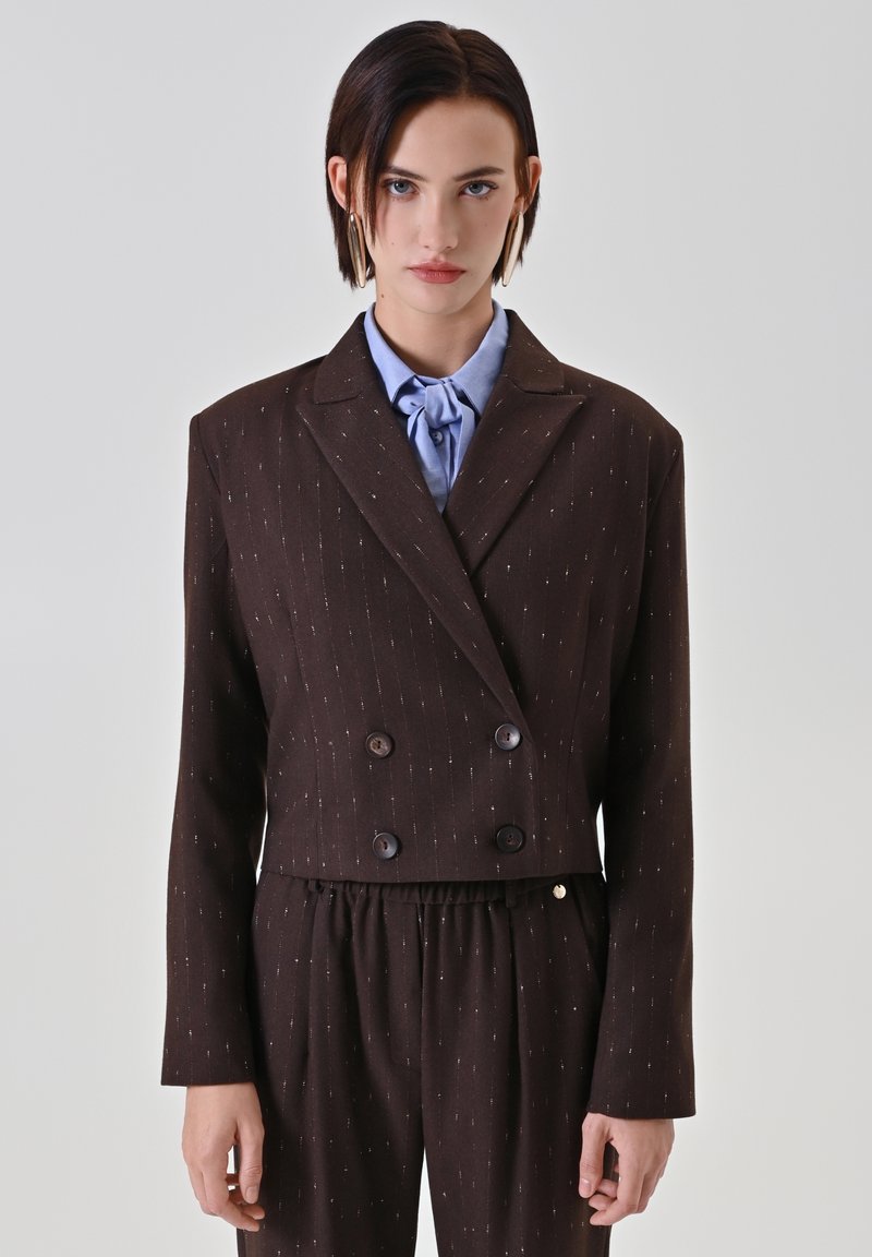 Brauner, zweireihiger, kurz geschnittener Blazer mit vertikalen Nadelstreifen, mit Reverskragen und Knopfdetails, kombiniert mit strukturierten, passenden Hosen.