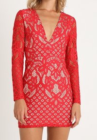 Robe en dentelle rouge à manches longues avec motifs floraux et en forme de losange. Décolleté plongeant en V, silhouette ajustée et texture transparente.