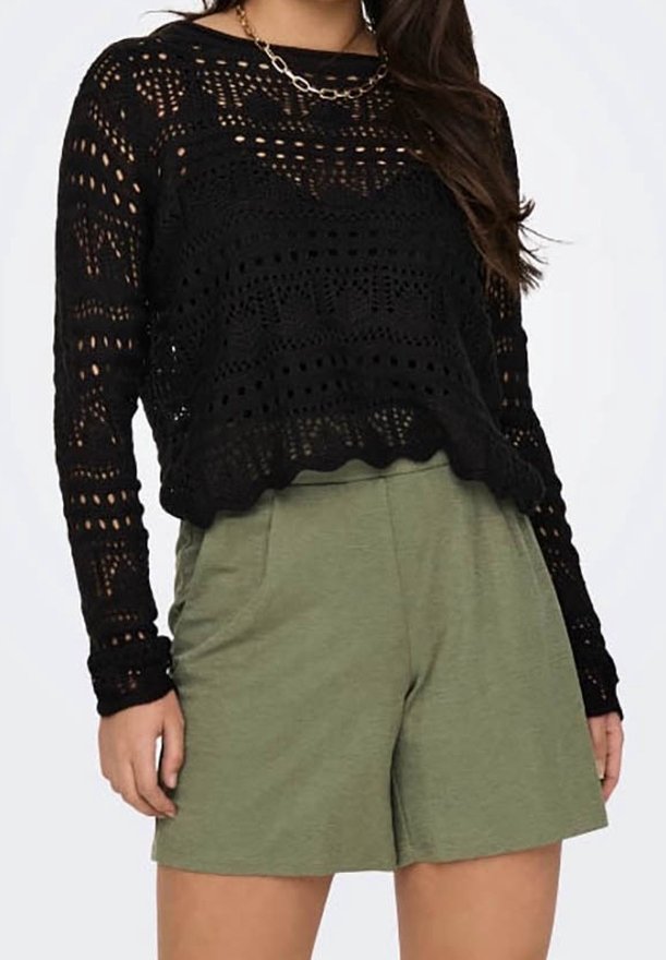 Femme portant un haut à manches longues noir en crochet, un collier chaîne en or et un short taille haute vert olive.