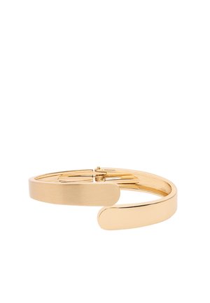 Bransoletka na zawiasach z metalu w złotym odcieniu, o eleganckim, zakrzywionym kształcie i gładkiej, polerowanej powierzchni.