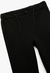 Sorte sweatpants lavet af tekstureret stof, med elastisk talje, justerbar snoretræk og knaplukning foran.