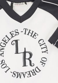 Witte T-shirt met zwarte V-hals en mouwen; heeft zwarte ronde borduurwerk met de tekst "LOS ANGELES - DE STAD VAN DROMEN" en "LR."