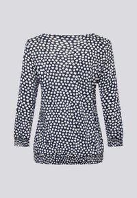 Marineblaues Langarmshirt mit weißen unregelmäßigen Polka-Dots, elastischen Bündchen und Saum, von hinten auf hellgrauem Hintergrund gezeigt.