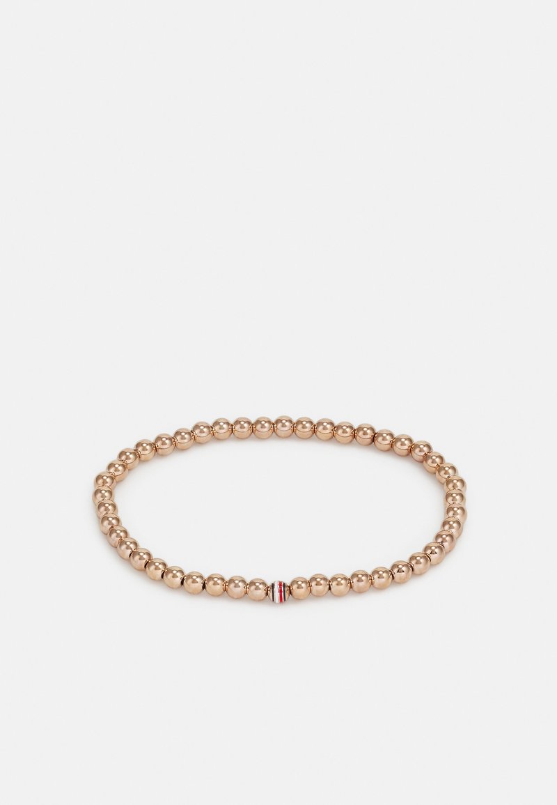 Bracelet élastique doré mettant en vedette des perles rondes en métal et une petite perle d'accent avec des rayures rouges et blanches pour un détail supplémentaire.