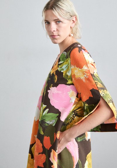 Blomsterkjole med brun basis, prydet med livlige oransje, rosa og grønne blomster. Korte ermer og lommer gir funksjonalitet.