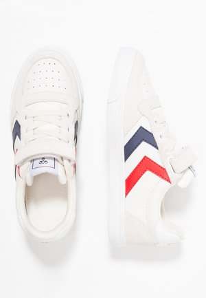 Baskets blanches avec une texture lisse, dotées d'accents zigzag bleu marine et rouge. Comprend des lacets et une sangle Velcro. Conception légère.