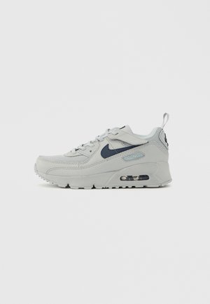 Baskets Nike Air Max grises avec une tige texturée, des panneaux en mesh, des accents bleu marine et un amorti à air visible dans la semelle.