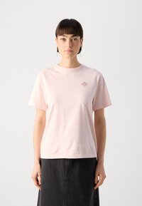 T-shirt in cotone rosa chiaro con maniche corte e scollo rotondo, con logo marrone piccolo nella zona sinistra del petto.