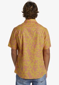 Korte mouwen shirt in roze en geel met een bloemenpatroon, gemaakt van lichte stof. Beschikt over een kraag en een knoopsluiting aan de achterkant.