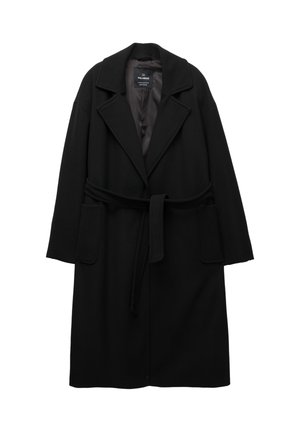 Manteau en laine noire mélangée avec un large col, une taille ceinturée et deux poches avant. Il présente une texture douce et un design minimaliste.
