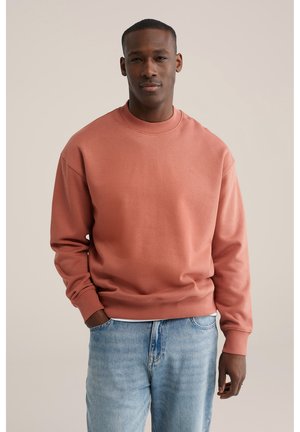 Zweetshirt in roestkleur met lange mouwen, een geribde crewneck en manchetten, gecombineerd met lichtblauwe denim jeans. Gemaakt van een gladde katoenmix.