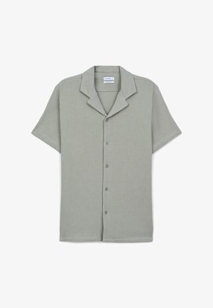 Camicia a maniche corte con bottoni di colore verde chiaro. Presenta un tessuto testurizzato con colletto a punta e chiusura anteriore con bottoni.