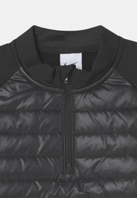Schwarze Hybridjacke mit einem gesteppte unteren Teil, glattem oberen Stoff, hohem Kragen und einem Teil-Reißverschluss für Belüftung.