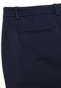 Granatowe eleganckie spodnie uszyte z teksturowanej tkaniny, wyposażone w jedną tylną kieszeń i szlufki na pasek, zaprojektowane w smukłej sylwetce.