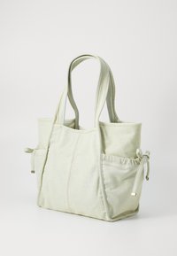 Borsa a tracolla in tela di colore verde chiaro con due tasche esterne, dettagli con cordoncino e doppi manici; presenta una lavorazione a punto sul corpo.