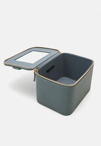 Square cosmetic case in soft gray faux leather with gold zipper, interior mirror, and a spacious, smooth-textured compartment.