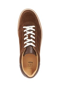 Brown suede sneaker with white laces, tan leather accents, rounded shape, smooth texture, and embossed logo on the insole.
