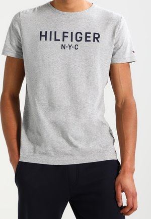Šedé tričko s krátkým rukávem vyrobené z bavlny, s kulatým výstřihem a tmavě modrým potiskem "HILFIGER NYC" na přední straně. Volný střih.