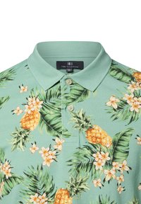 Hellgrünes Poloshirt mit einem tropischen Muster aus gelben Ananas, weißen Blumen und grünen Blättern. Mit zwei Knöpfen auf der Knopfleiste.