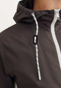 Brown lightweight jacket with a hood, featuring a white zipper and adjustable drawstring with black accents and patterned ends.