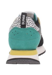 Zapatilla multicolor con un talón de ante en color azul verdoso, malla negra, tejido gris con puntos y acentos amarillos. Presenta una entresuela blanca y una suela exterior negra texturizada.