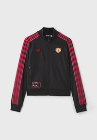 Črna zip-up bunda z rdečimi črtami, ki tečejo po rokavih, izvezenim logotipom na prsih in obližem na spodnjem levem delu. Mehka tkanina.