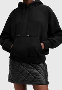 Black pullover hoodie with drawstrings and front pocket, paired with a black quilted leather mini skirt featuring a diamond pattern.