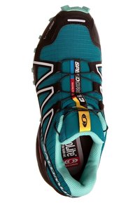 Turkos löparsko med svarta, vita och gula detaljer. Har en texturerad ovandel, förstärkt tåhätta och halksäker yttersula.