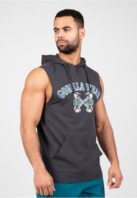 Mouwloze donkergrijze hoodie van zacht materiaal, met een voorzak en een grafische print met halters in blauwe en witte accenten.