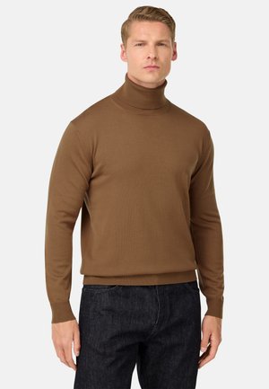 Suéter marrón de cuello alto en un diseño de punto ajustado, hecho de material suave con acentos de canalé en el cuello y los puños, combinado con jeans oscuros.