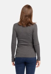 Maglia grigia a maniche lunghe con design aderente, texture morbida e orlo arrotondato, abbinata a jeans in denim blu. Vista dal retro.