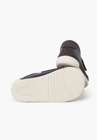 Scarpe nere in velcro con tomaia texturizzata, materiale morbido e suola in gomma bianca con scanalature per aderenza. Made in Spain.