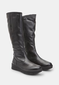 Fekete bőr, térd fölé érő csizmák sima textúrával, oldalsó cipzárral, lekerekített orral és lapos gumi talppal. Modern dizájn minimális részletezéssel.
