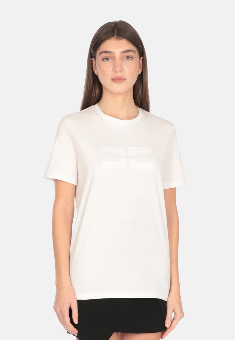 Camisa de algodón blanca de manga corta, con un sutil patrón geométrico tonal en el frente y un escote redondo.