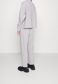Gray knit cropped sweatshirt and matching pants, featuring a relaxed fit and side slits. Paired with chunky black platform shoes.