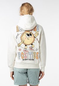 Lichtbeige hoodie, met een kleurrijke cartoon zonafbeelding op de rug en de tekst "BLIJF ALTIJD POSITIEF" en "WEES GELUKKIG SAMEN". Soepele textuur.