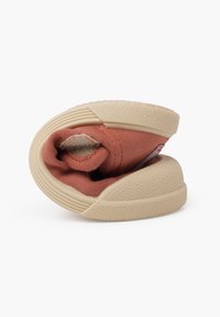 Scarpe in tessuto morbido di colore corallo con una suola in gomma beige, caratterizzate da una finitura testurizzata e una forma arrotolata per una conservazione compatta.