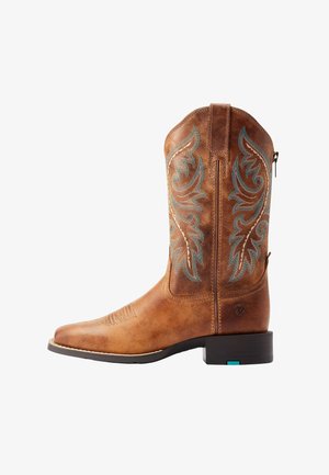 Botte de cowboy en cuir marron avec des motifs de flammes brodés en bleu et beige et un petit talon noir sur fond blanc.
