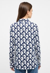 Long-sleeve shirt featuring a navy and white geometric pattern, with a smooth texture and a slightly curved hemline.