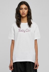 Balta medvilninė marškinėliai trumpomis rankovėmis, su purpuriniu siuvinėtu užrašu "Baby Girl" priekyje. Laisvas siluetas su tiesiu pjūviu.